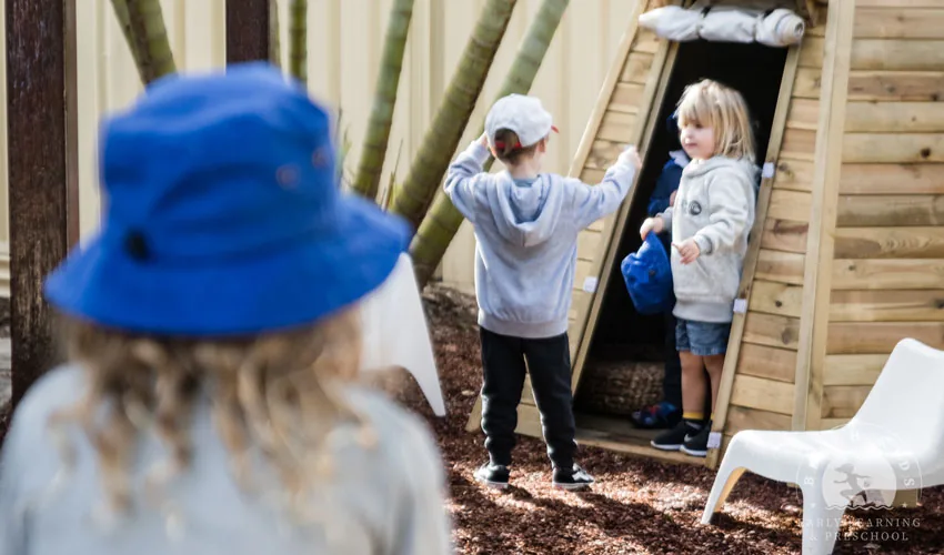 Children playing at the timber cubby house in the Cabarita yard
